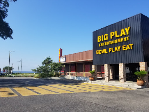 A Pelican Underground Llc plumber checks for pipe problems outside a big bowling alley with a mostly empty parking lot nearby.