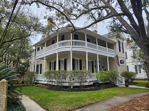 Pelican Underground LLC plumber arrives for trenchless sewer repair at a welcoming Southern-style home with an American flag.