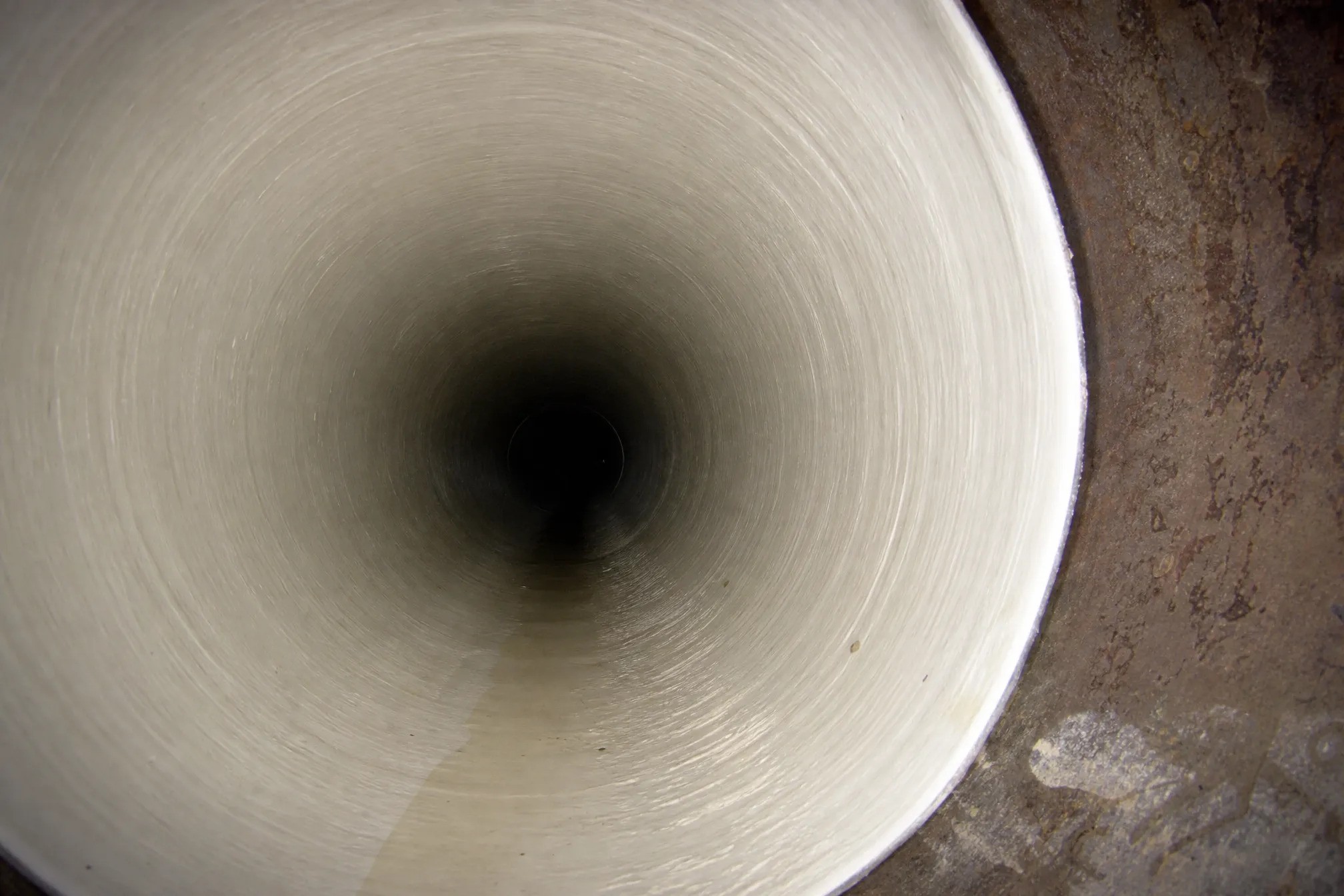 Looking into a deep tunnel by Pelican Underground LLC, showing its rounded shape and shadowed center.